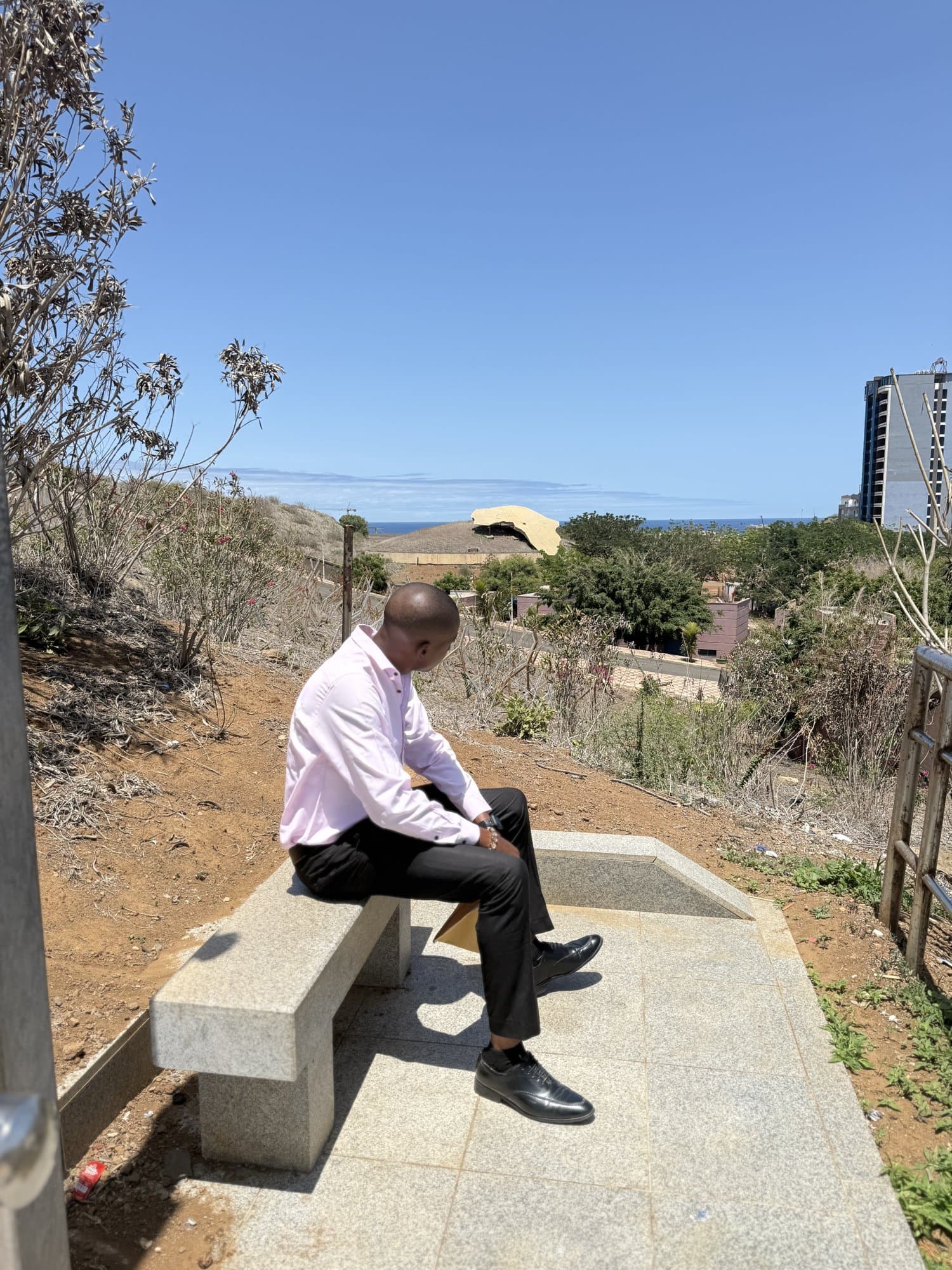 Jordan sitting on a hillside bench in Dakar