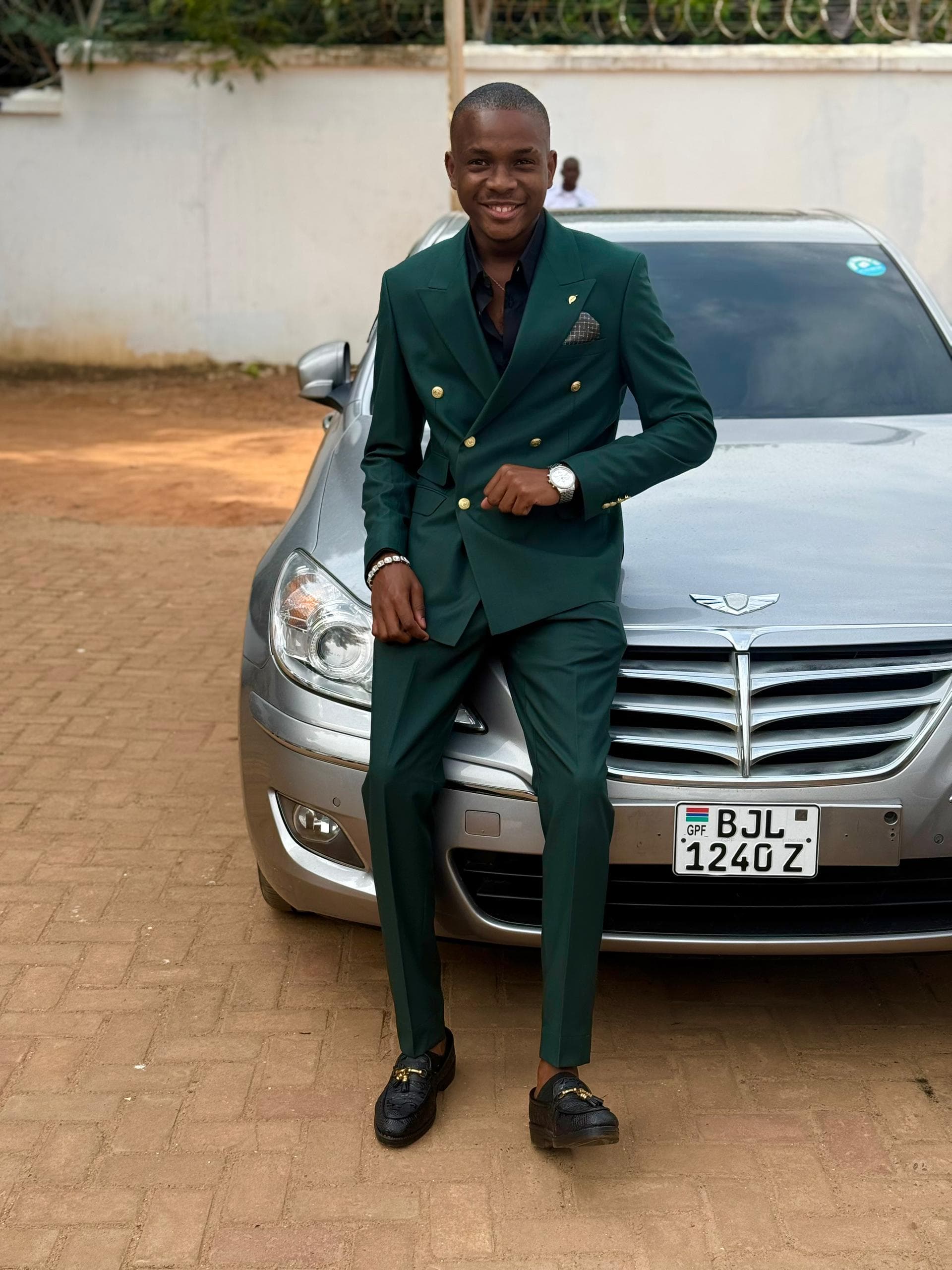 Jordan seated on the hood of a car in a green suit