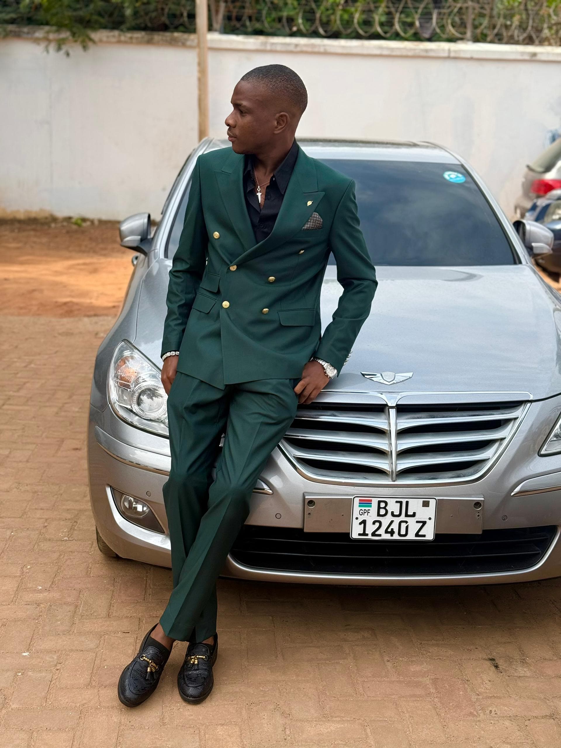 Jordan in a green double-breasted suit leaning against a car