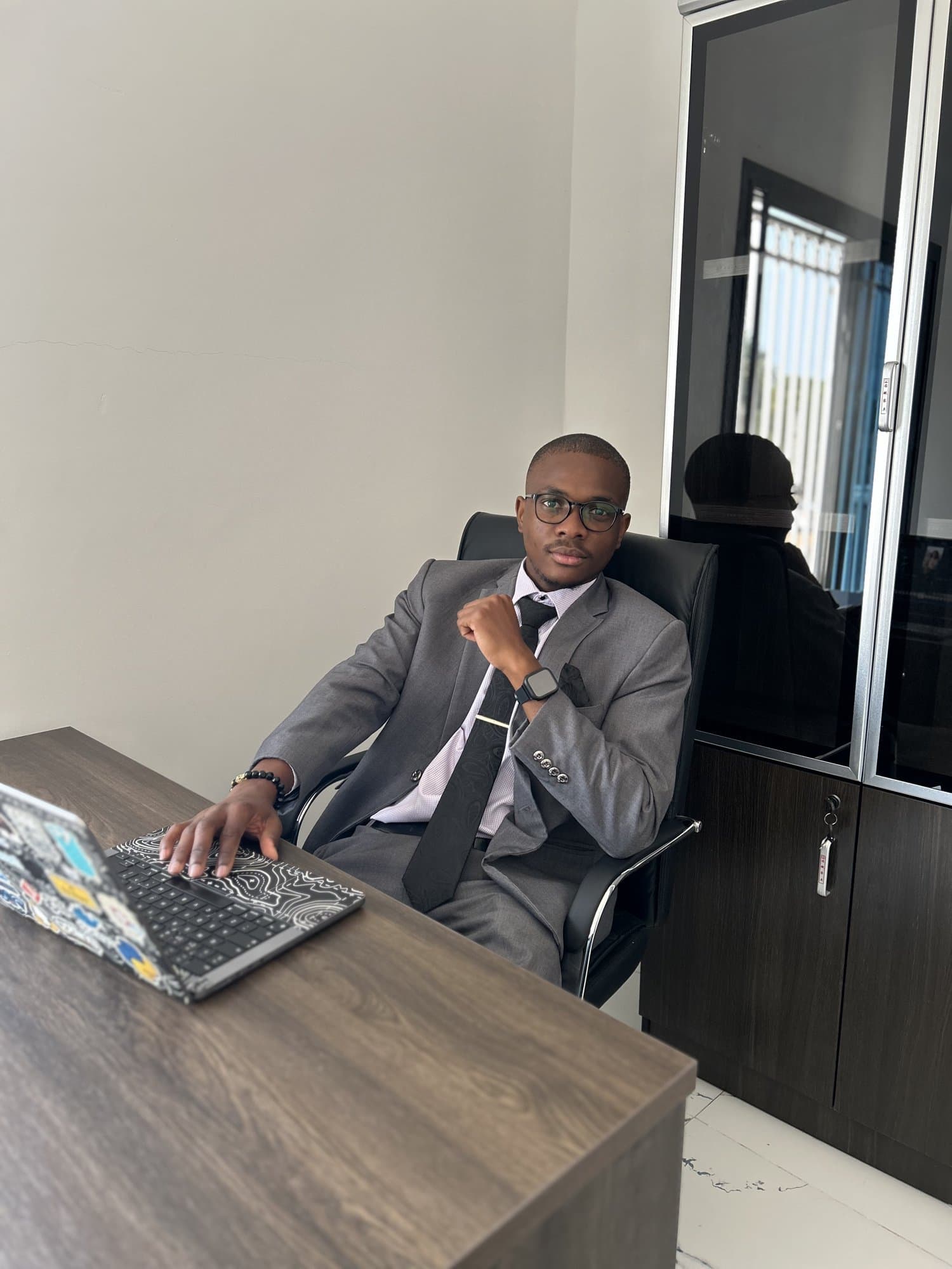 Jordan in a grey suit gesturing at his desk