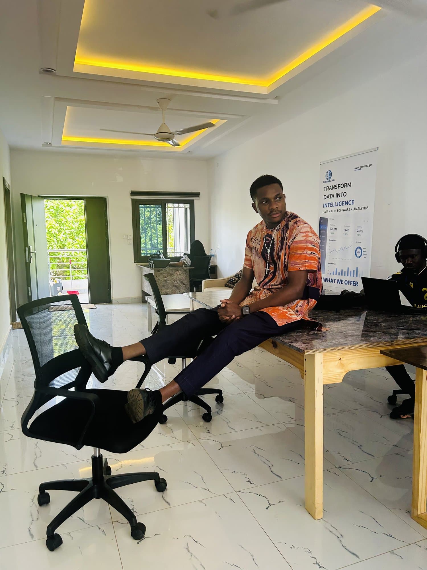 Wide shot of Jordan with his feet up in the office